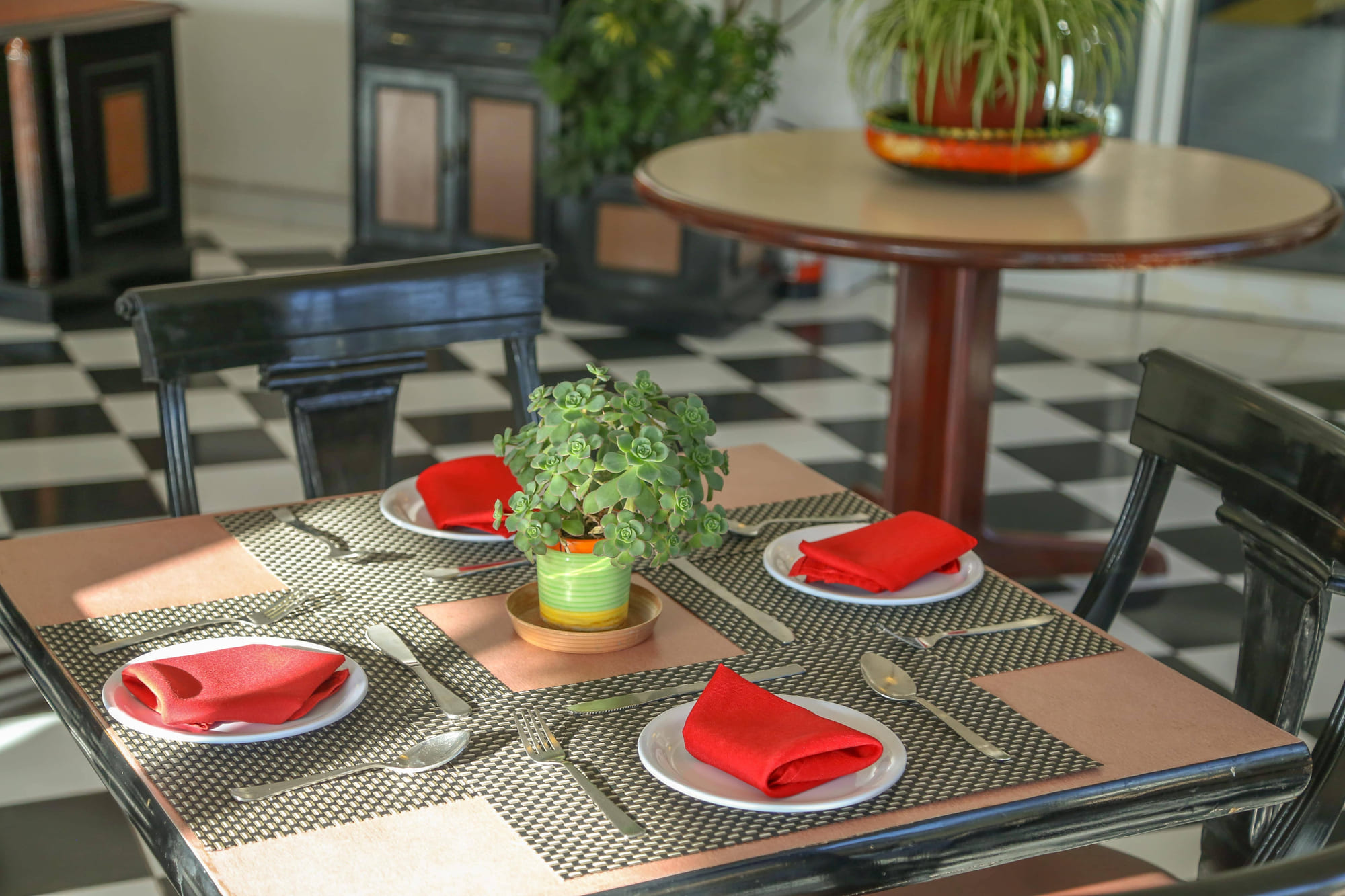 A restaurant table set with red napkins and a small succulent